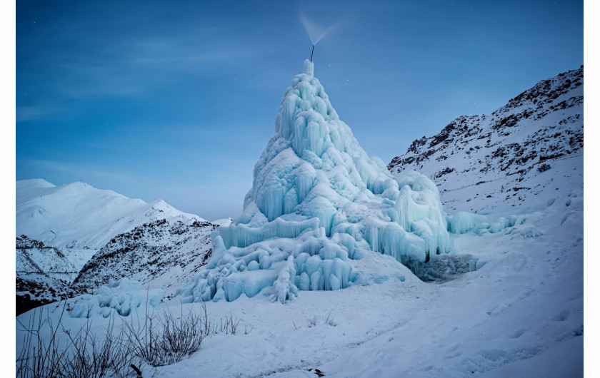 fot. Ciril Jazbec, Słowenia, z cyklu: One Way to Fight Climate Change: Make Your Own Glaciers dla National Geographic, 2 miejsce w kategorii Środowisko - seria zdjęć / World Press Photo 2021

Gdy himalajskie śniegi maleją, a lodowce ustępują, społeczności w regionie Ladakh w północnych Indiach budują ogromne lodowe stożki, które zapewniają wodę w lecie. Ladakh to zimna pustynia, z temperaturami zimą sięgającymi -30°C i średnimi opadami deszczu wynoszącymi około 100 milimetrów. Większość wiosek boryka się z dotkliwym brakiem wody, szczególnie w kluczowym okresie sadzenia roślin w kwietniu i maju. W 2013 roku Sonam Wangchuk, inżynier i innowator z Ladakhi, wymyślił metodę tworzenia sztucznych lodowców w formie stożkowatych zwałów lodu, przypominających buddyjskie stupy religijne. Lodowe stupy magazynują zimową wodę roztopową i powoli uwalniają ją wiosną, w okresie wegetacyjnym, kiedy jest ona najbardziej potrzebna do upraw. Stupy powstają w zimie, kiedy woda jest odprowadzana podziemnymi rurami z wyżej położonych terenów. Końcowy odcinek wznosi się pionowo, a różnica wysokości powoduje, że w temperaturach poniżej zera woda tryska na zewnątrz, zamarzając i tworząc stupę. Stupy zostały zbudowane w 26 wioskach w 2020 roku, a obecnie trwa budowa rurociągu, który ma stworzyć 50 kolejnych. Wangchuk, mówi, że stupy stanowią ostatnią szansę himalajskich społeczności górskich na walkę z kryzysem klimatycznym, ale nie powinny być traktowane jako rozwiązanie tego problemu: pozostaje to w gestii rządów krajowych, a także ludzi prowadzących przyjazny dla środowiska styl życia w celu zmniejszenia emisji.
